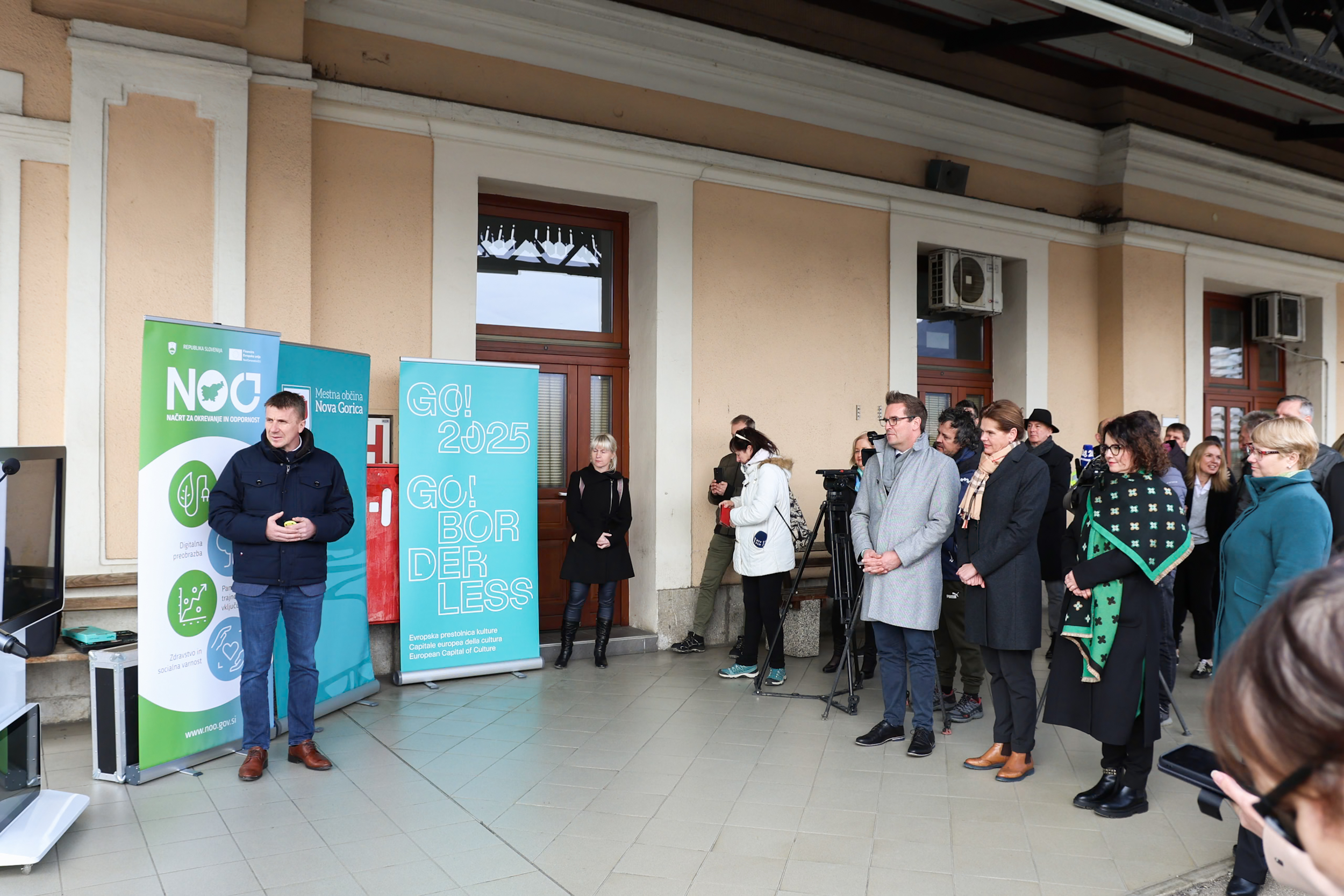 Udeleženci slovesnosti stojijo na železniški postaji v Novi Gorici