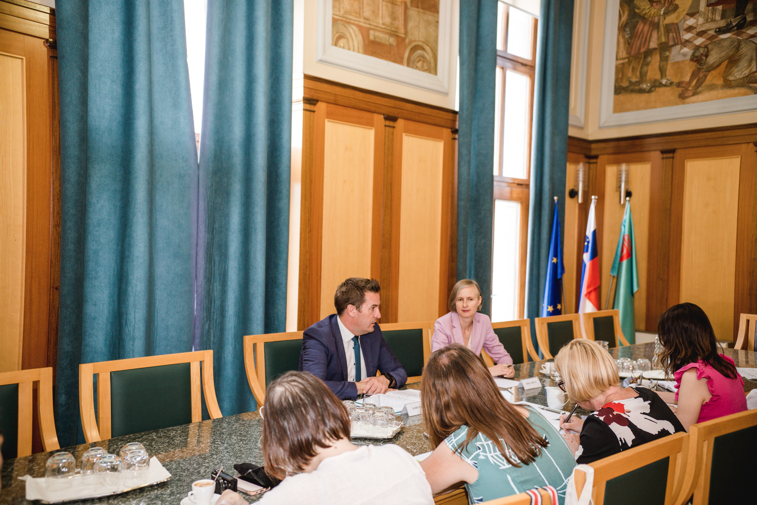 Udeleženci novinarske konference skupaj z županom sedijo za mizo v Zeleni dvorani občinske stavbe