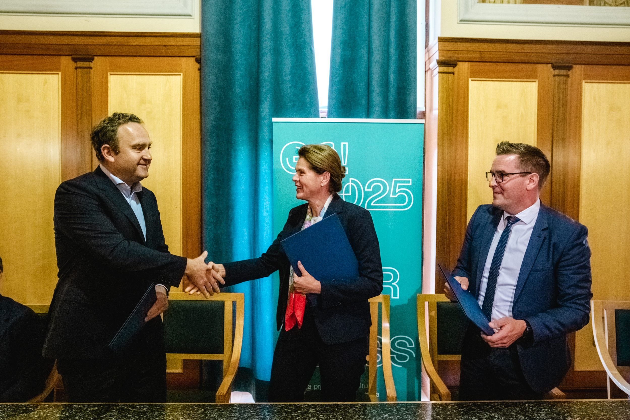 Ministrica za infrastrukturo se rokuje z direktorjem Slovenskih železnic, ob njiju s Sporazumom v roki stoji novogoriški županji