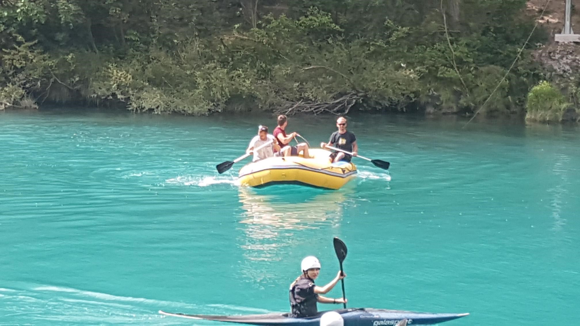 Trije moški sedijo na gumijastem čolnu in veslajo