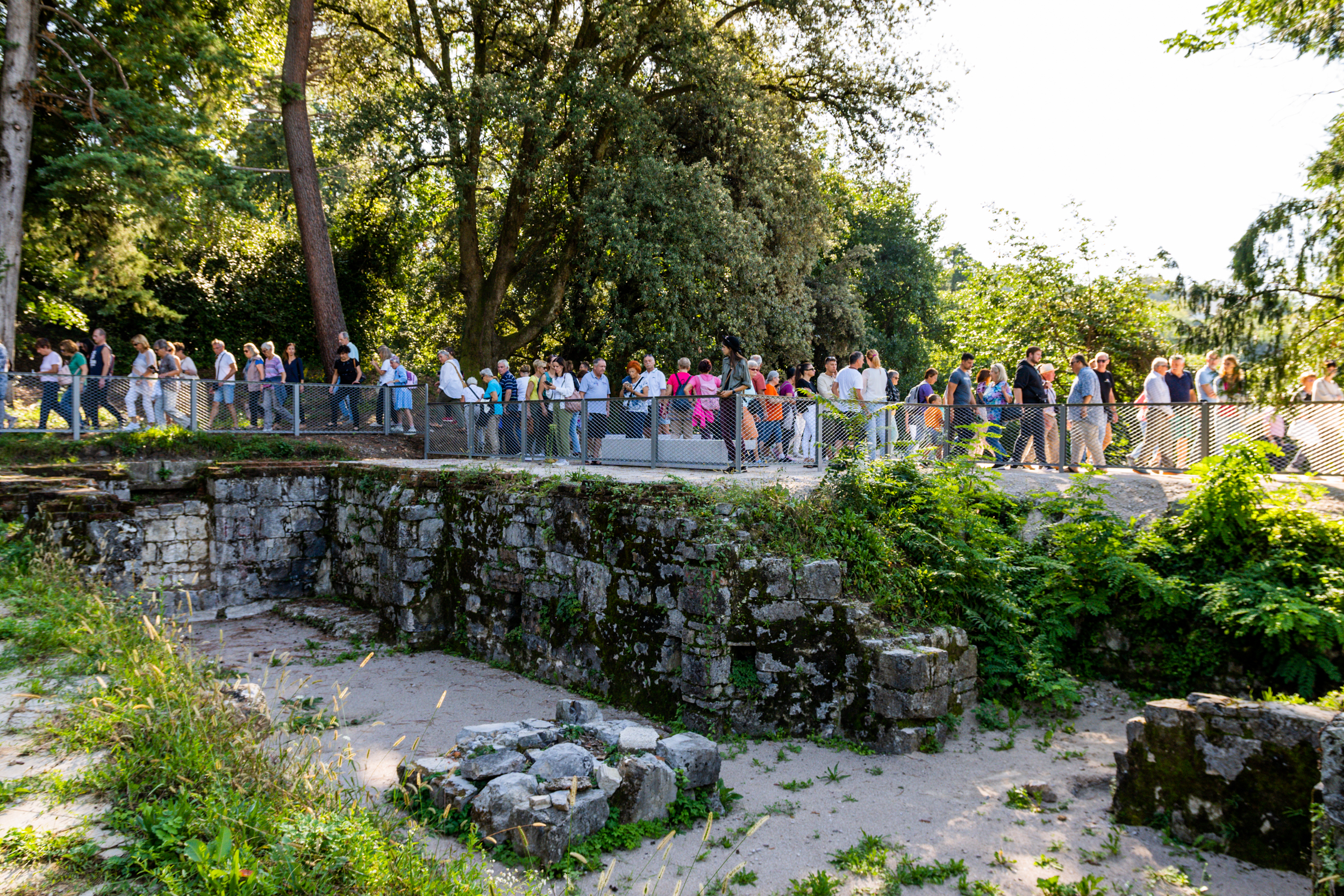 Množica ljudi se sprehaja po kamnitem mostičku v Rafutskem parku
