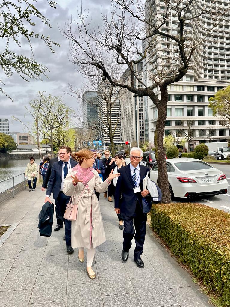 (Z leve) Vodja Kabineta župana Mija Lorbek z direktorjem japonske banke Mizuho ter novogoriškim županom Samom Turelom v ozadju s skupino drugih udeležencev hodijo po mestnem pločniku ter